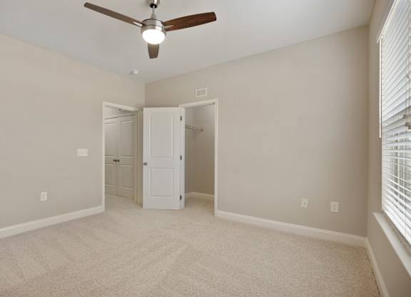 A room with a ceiling fan and carpeted floor.