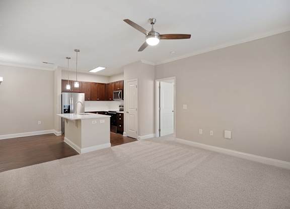 A spacious living room with a kitchen in the background.