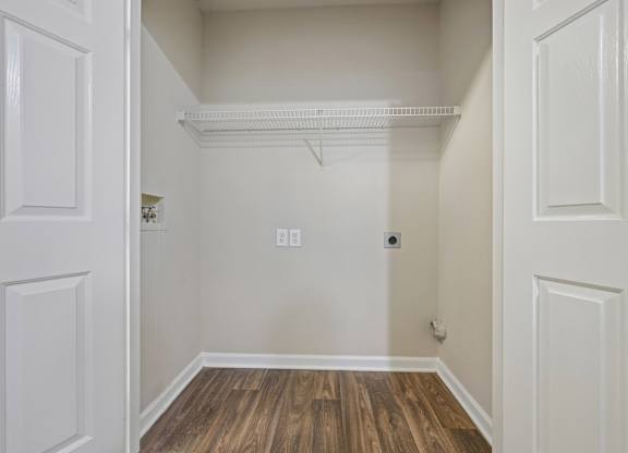 A white closet with a wooden floor and a white door.
