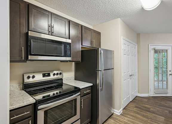 A kitchen with a stove, oven, microwave, and refrigerator.