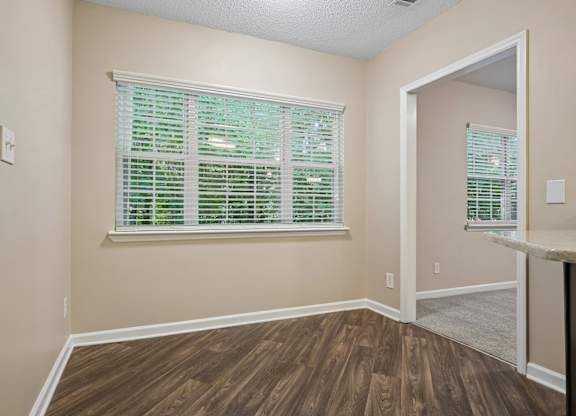 A room with wooden floors and a window with green blinds.