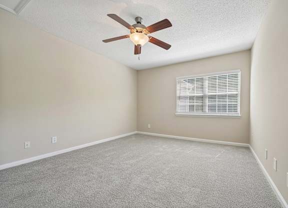 A room with a ceiling fan and carpeted floor.