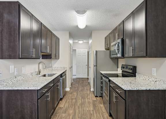 A kitchen with dark brown cabinets and a white counter top.