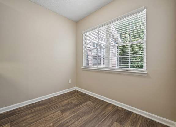 A room with a window and wooden flooring.