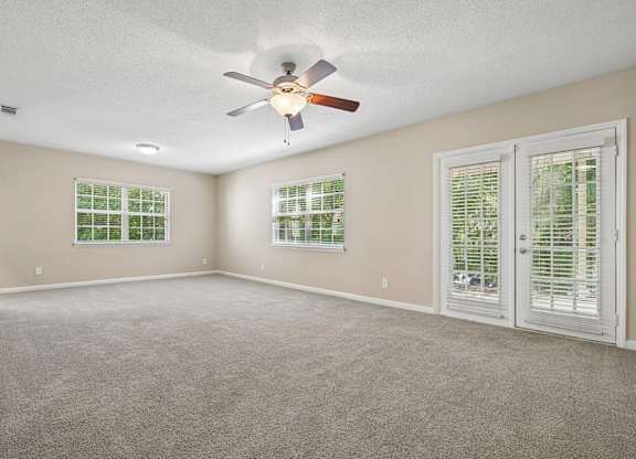 A room with a ceiling fan and two windows with blinds.