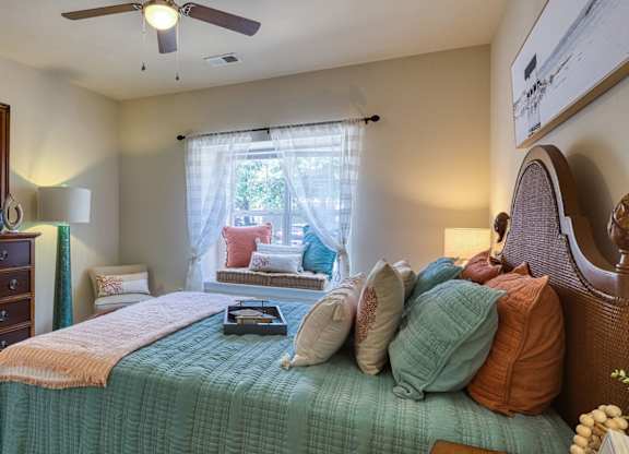 A bedroom with a bed, dresser, mirror, and window.