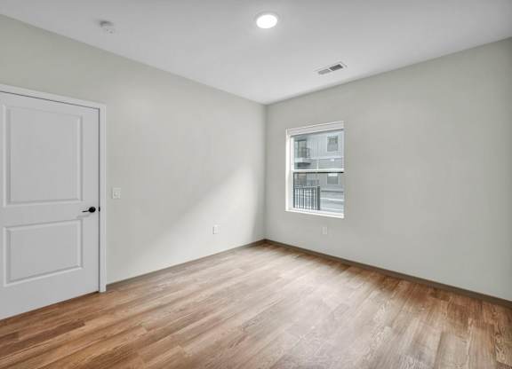 A room with a white door and a window with blinds.