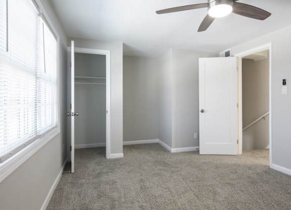 A room with a ceiling fan and a window with blinds.
