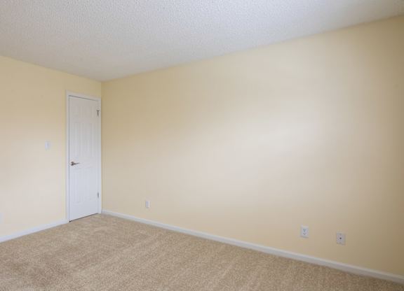 A room with a white door and beige walls.