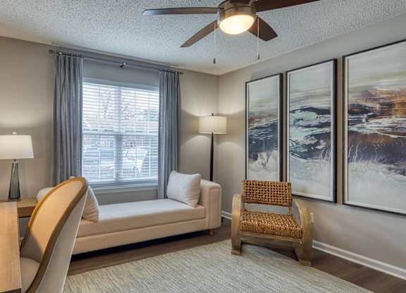 A living room with a couch, a chair, a table, and a ceiling fan.