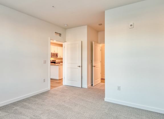 A spacious room with white walls and a carpeted floor.