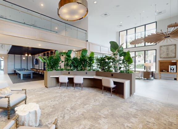 a large lobby with a table with chairs and plants