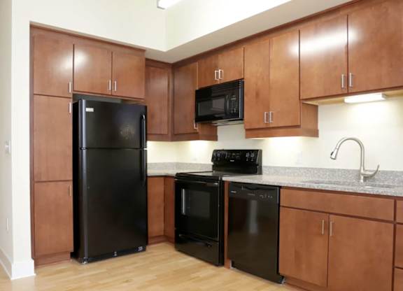 A kitchen with black appliances and wooden cabinets.