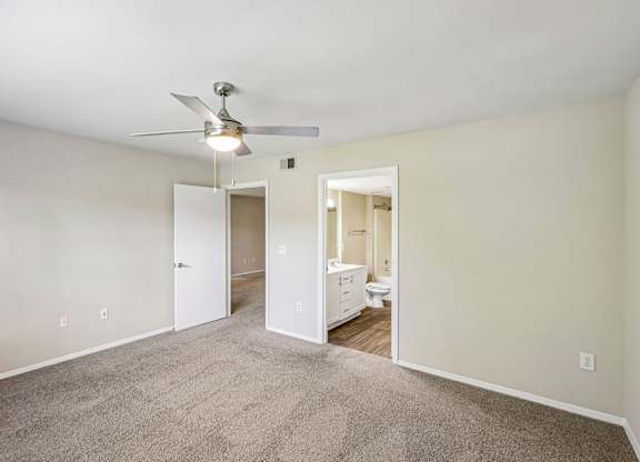 A room with a ceiling fan and carpeted floor.