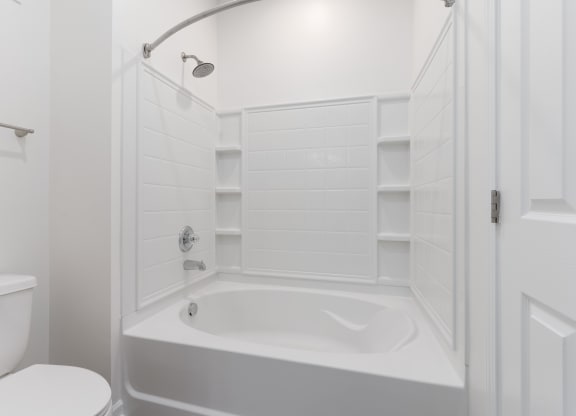 a white bathroom with a tub and a toilet at The Charleston, Columbus