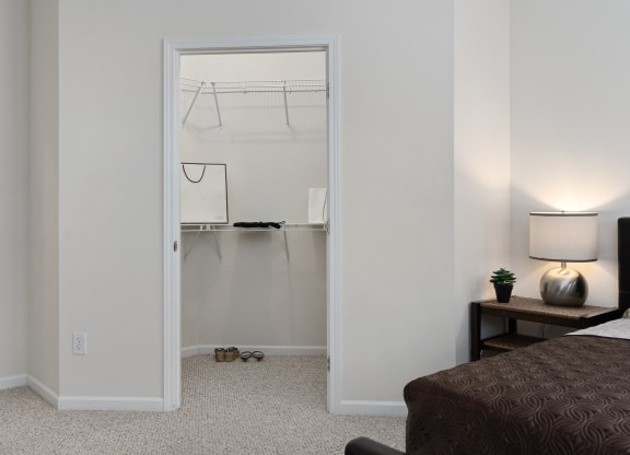 a bedroom with a closet and a bed and a night stand with a lamp at The Charleston, Columbus
