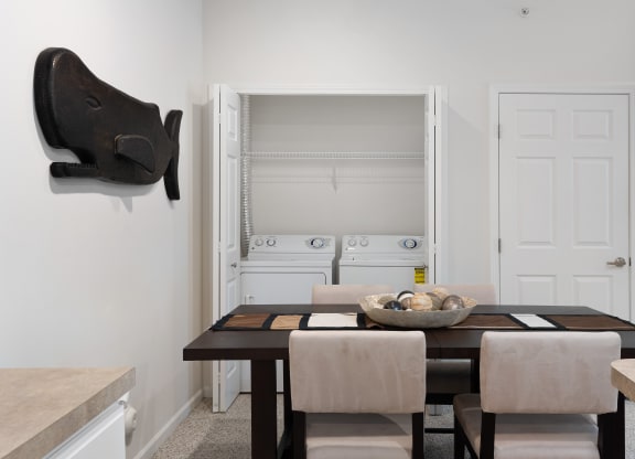a dining room with a wooden table and chairs and a white kitchen with a sink at The Charleston, Columbus, OH, 43221