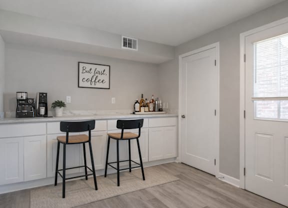 A kitchen with a bar area and two stools.