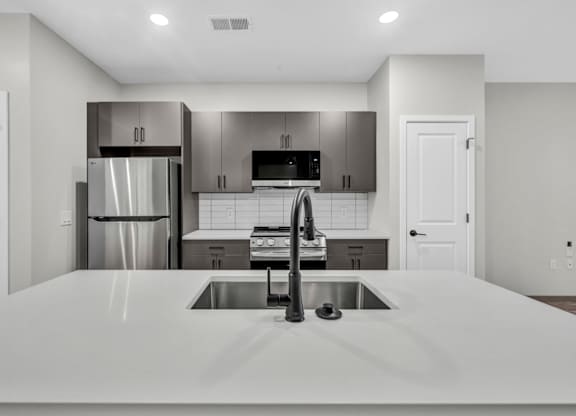 A modern kitchen with a stainless steel refrigerator and a white countertop.