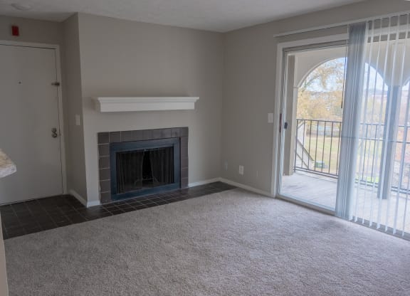 an empty living room with a fireplace and a patio door