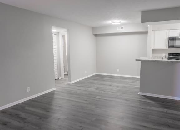 an empty living room and kitchen with wood flooring
