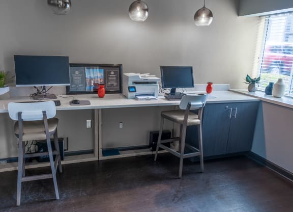 a computer desk with three stools and two monitors