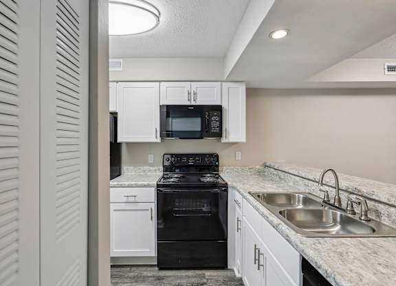 A kitchen with a black stove top oven and a microwave above the stove.