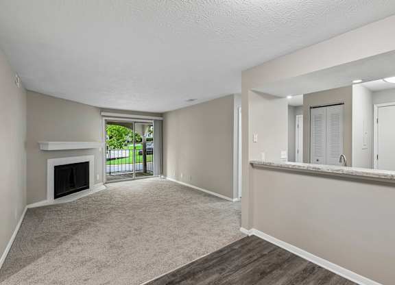 A spacious living room with a fireplace and a view of the backyard.