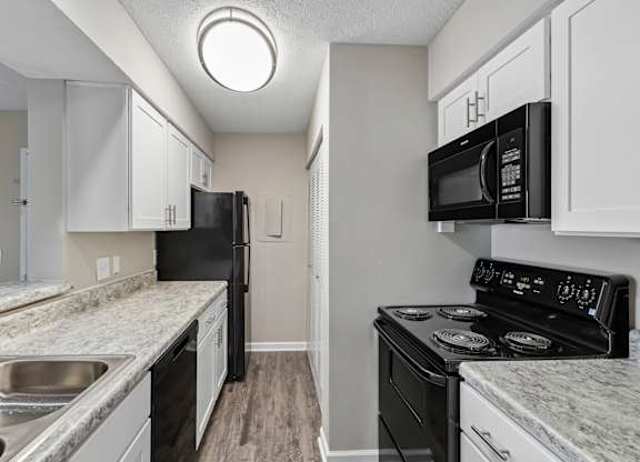 A kitchen with black appliances and white cabinets.