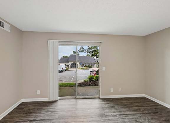 A room with a sliding glass door leading to a parking lot.