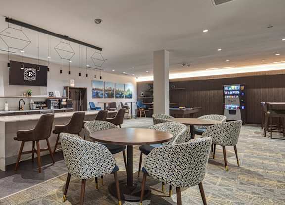 A modern dining area with a kitchen in the background at Residences at Richmond Trust in Richmond, VA, 23219