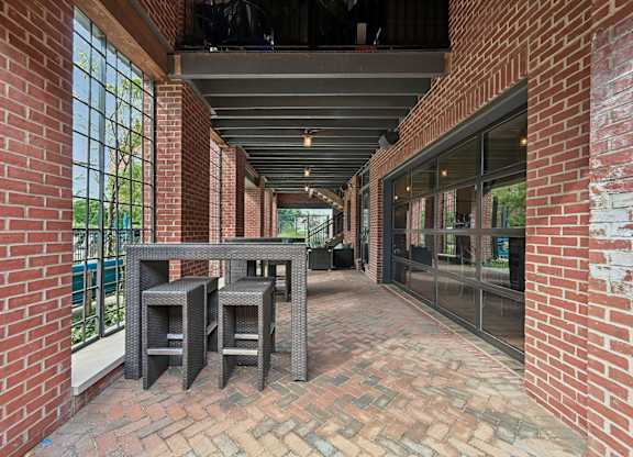 A patio with a table and chairs is surrounded by red brick walls.