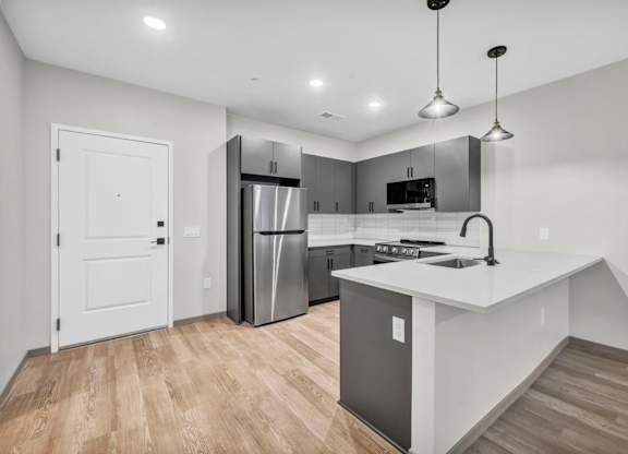 A modern kitchen with a white countertop and stainless steel appliances.