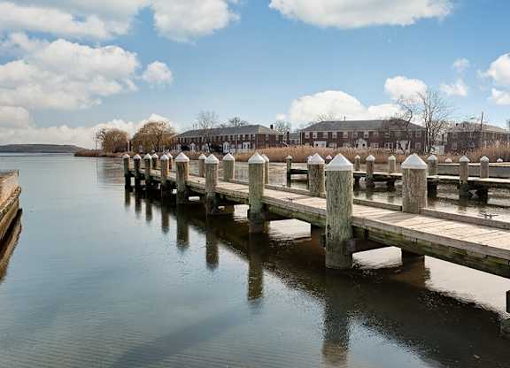 A wooden pier extends into a calm body of water with a building in the background.