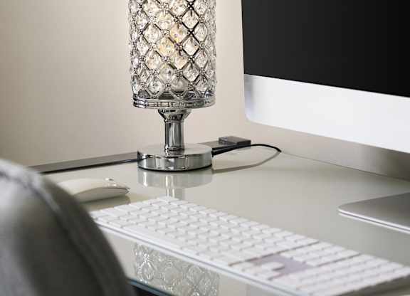 A glass lamp with a diamond pattern stands on a desk next to a computer monitor, keyboard, and mouse.