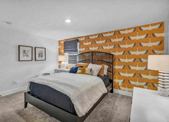 A bedroom with a bed, pillows, and pictures on the wall.