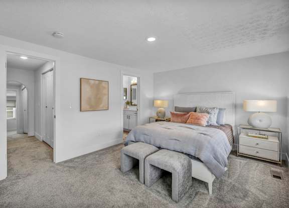 A bedroom with a bed, nightstand, and a grey tufted bench.