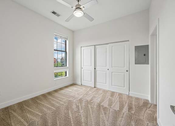 A room with a ceiling fan and carpeted floor.