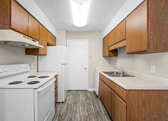 A kitchen with white appliances and wooden cabinets.