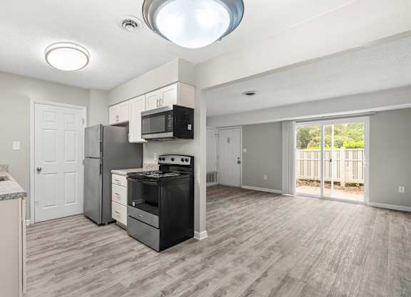 A kitchen with a black stove top oven and a microwave above the stove.