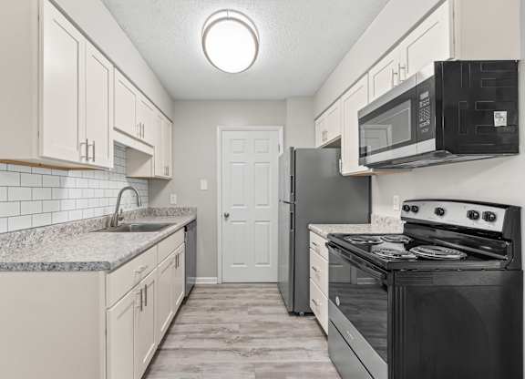 A kitchen with black appliances and white cabinets.