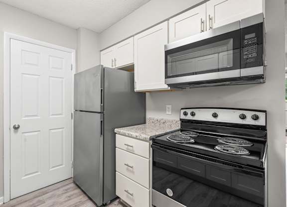 A kitchen with a stove, refrigerator, and microwave.