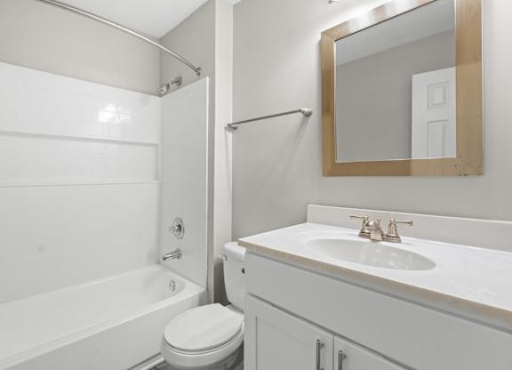 A white bathroom with a toilet, sink, and bathtub.