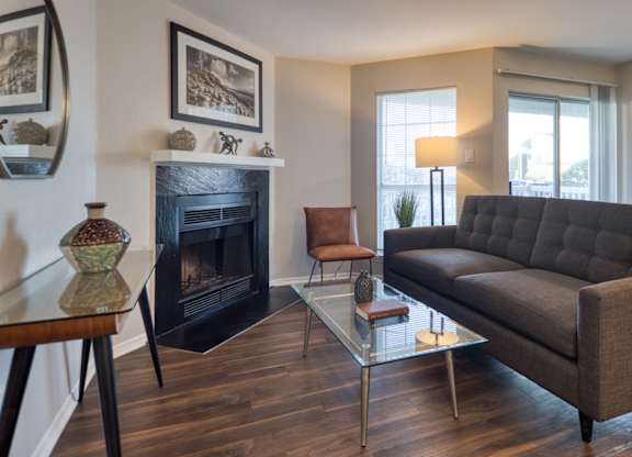 A living room with a black fireplace and a grey couch.