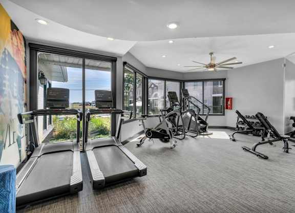 A spacious gym with treadmills, exercise bikes, and a fan.