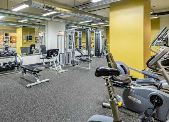 A gym with a variety of equipment including treadmills, weights, and exercise machines.