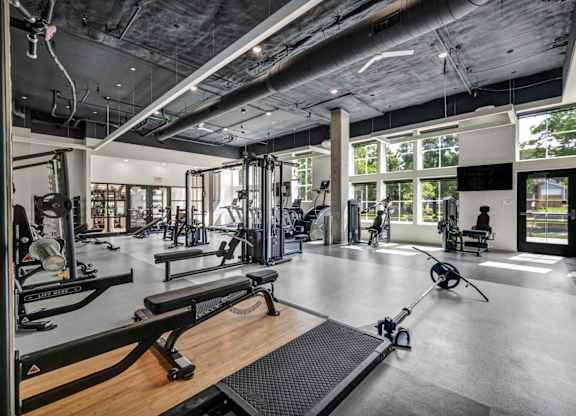 A gym with a variety of equipment including weights, benches, and a rowing machine.