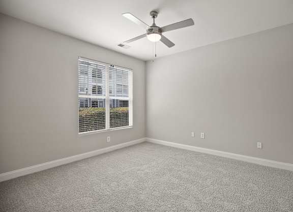 A room with a ceiling fan and a window with blinds.
