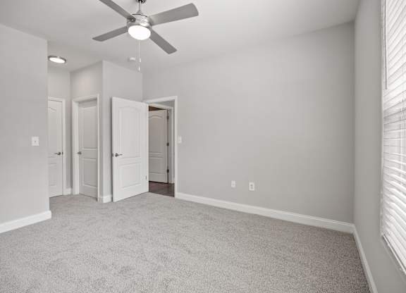 A room with a ceiling fan and carpeted floor.