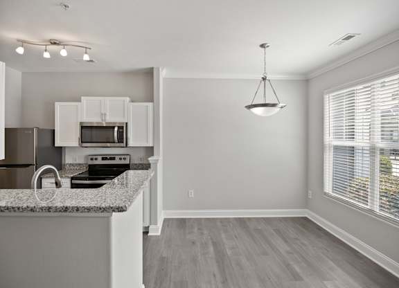 A kitchen with granite countertops and white cabinets.